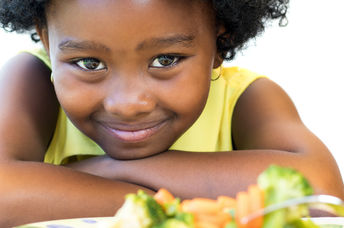 一个有一盘健康食品的年轻女孩微笑。