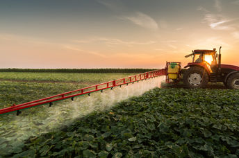 拖拉机在春季喷洒蔬菜田。
