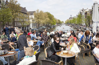 人们享受坐在阿姆斯特丹户外咖啡馆里的Gezellig生活。