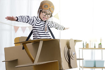Creative Little Girl在纸板箱中“飞”时使用了自己的想象力。