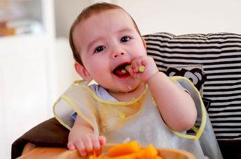 可爱的婴儿吃煮熟的蔬菜。