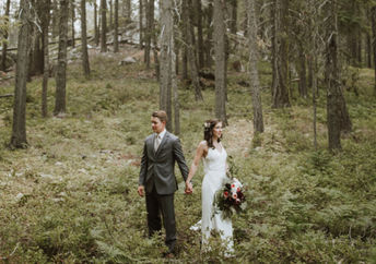 一对夫妇在婚礼礼服和衣服立场在森林里。