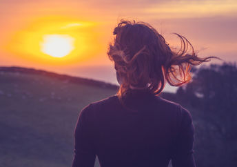 一个女人在正念的启发下敬畏地散步欣赏日落