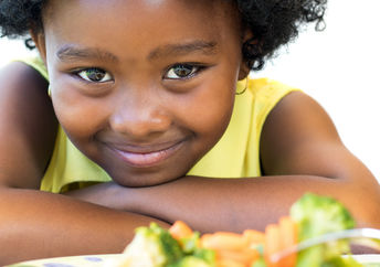 一个拿着一盘健康食品的年轻女孩微笑着。