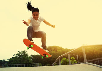 一个微笑的女孩做奥利在滑板公园移动。