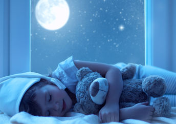 一个小女孩拥抱一只玩具熊与窗外的满月闪耀。