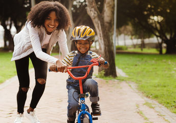 母亲教她的孩子如何骑自行车。