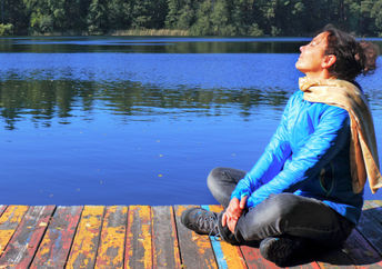 一个坐在湖边的码头上的女人正在做呼吸运动，以帮助她的迷走神经。