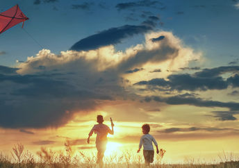 儿童在日落的田野中发射风筝