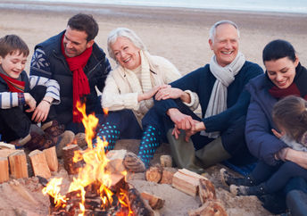 祖父母，父母和孩子通过在海滩篝火旁度过时光来联系。