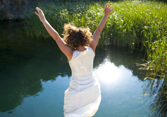 年轻女子跳入一个田园诗般的湖泊。