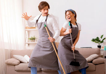 开朗的夫妇在春天打扫房屋时玩得开心和跳舞。