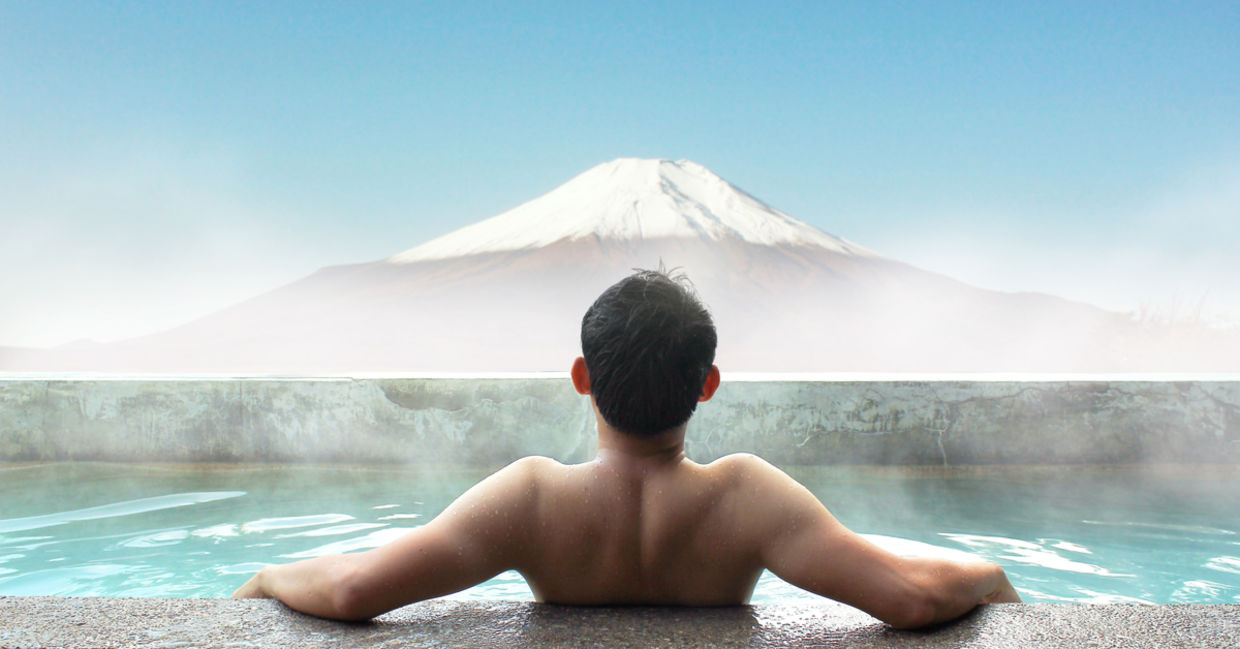 一个泡在温泉里的日本人凝视着富士山。