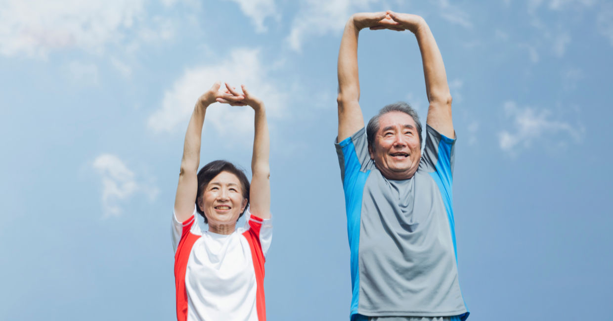 一对年长的日本夫妇在蓝天下伸展身体。