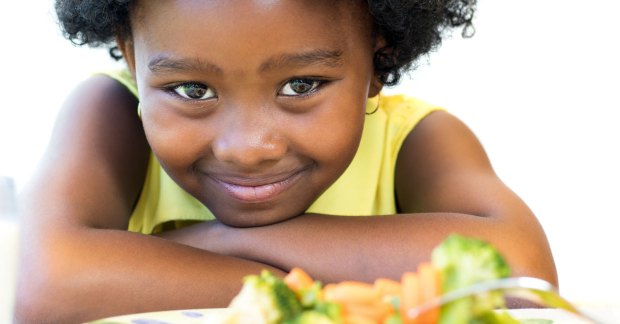 一个拿着一盘健康食品的年轻女孩微笑着。