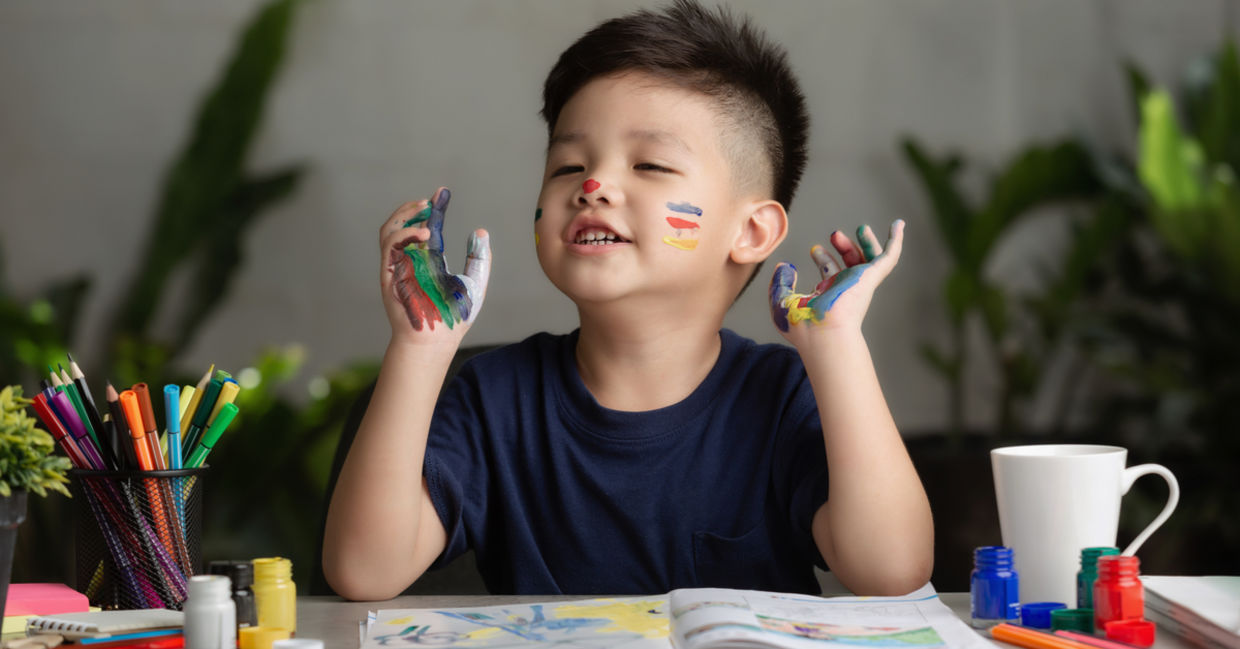 一个小男孩高兴地在手上和脸上涂满了颜料。