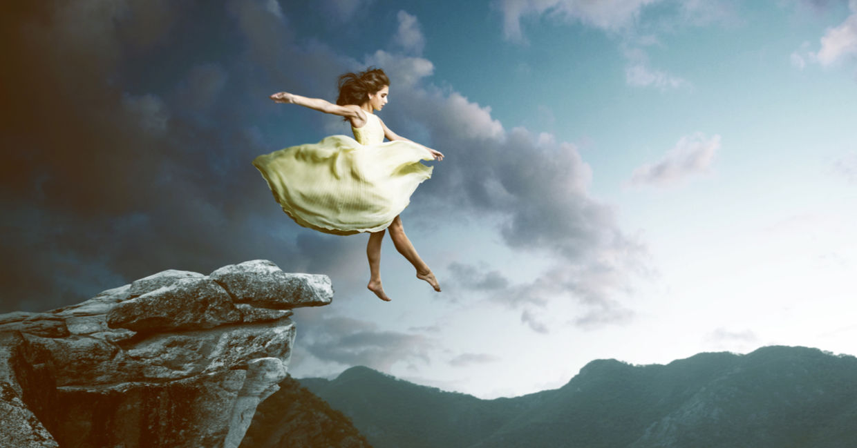 梦幻般的画面：一个穿着波浪形连衣裙的女人从高高的悬崖上漂下来。
