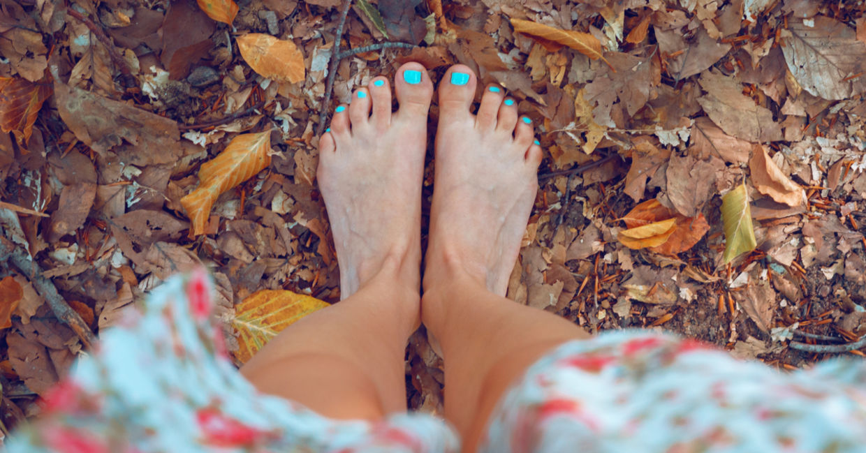 一个女人光着脚站在秋叶上。