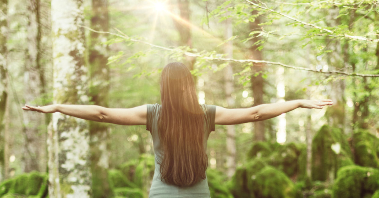 森林里的一位妇女张开双臂，表现出平衡与和谐。