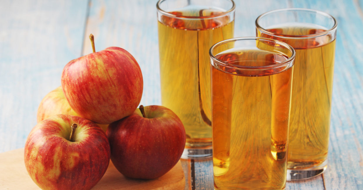杯自制的苹果汁放置在苹果的旁边。