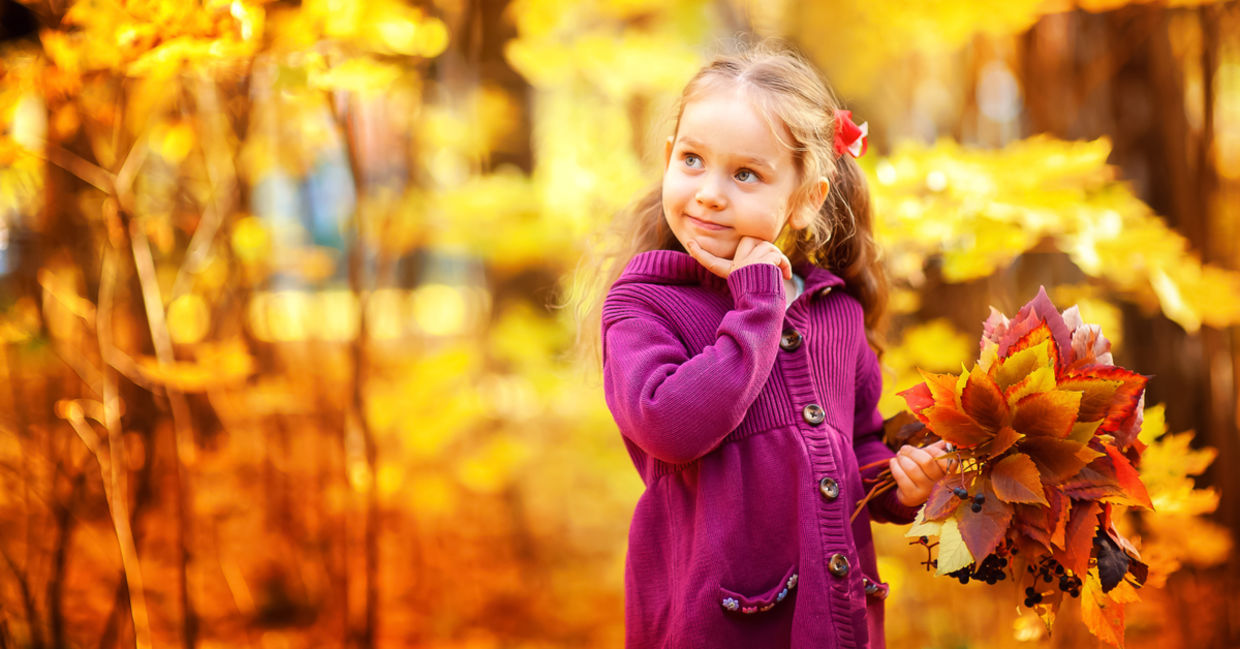 秋天槭树橙色叶子的愉快的小女孩