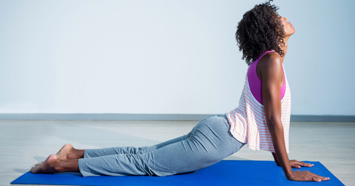 女人做眼镜蛇瑜伽姿势在健身房运动垫。