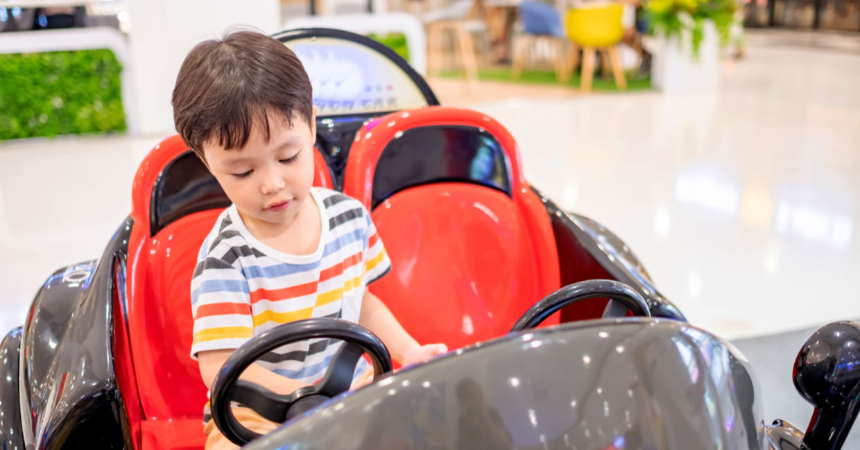 一个小男孩骑着硬币操作的汽车。