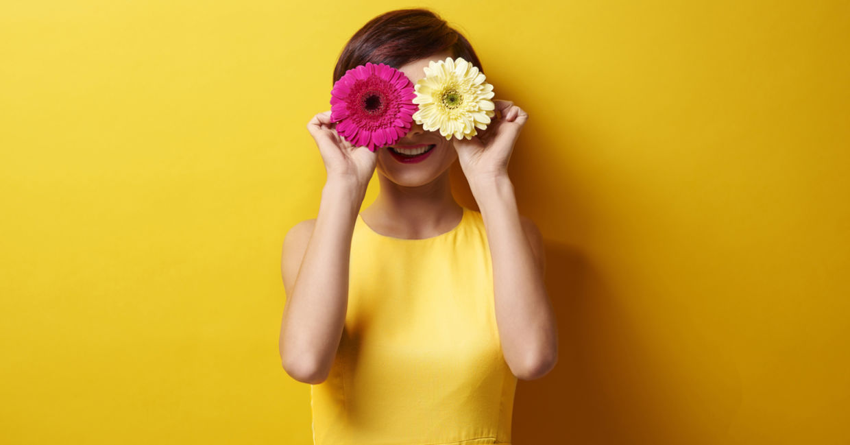 快乐的女人用鲜花遮住眼睛