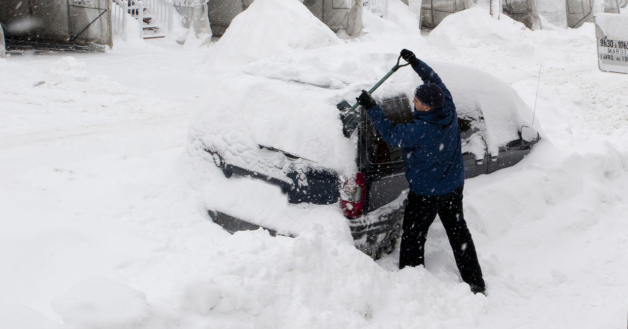 一个男人使用铲子挖出深雪的车。