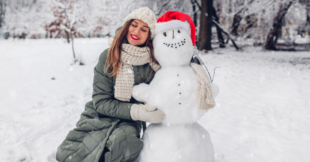 幸福在寒冷的冬天，一个女人拥抱一个雪人。