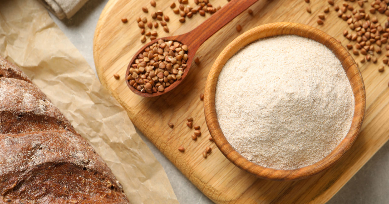 荞麦仁和荞麦面粉旁边是一条新鲜烘烤的无麸质面包。
