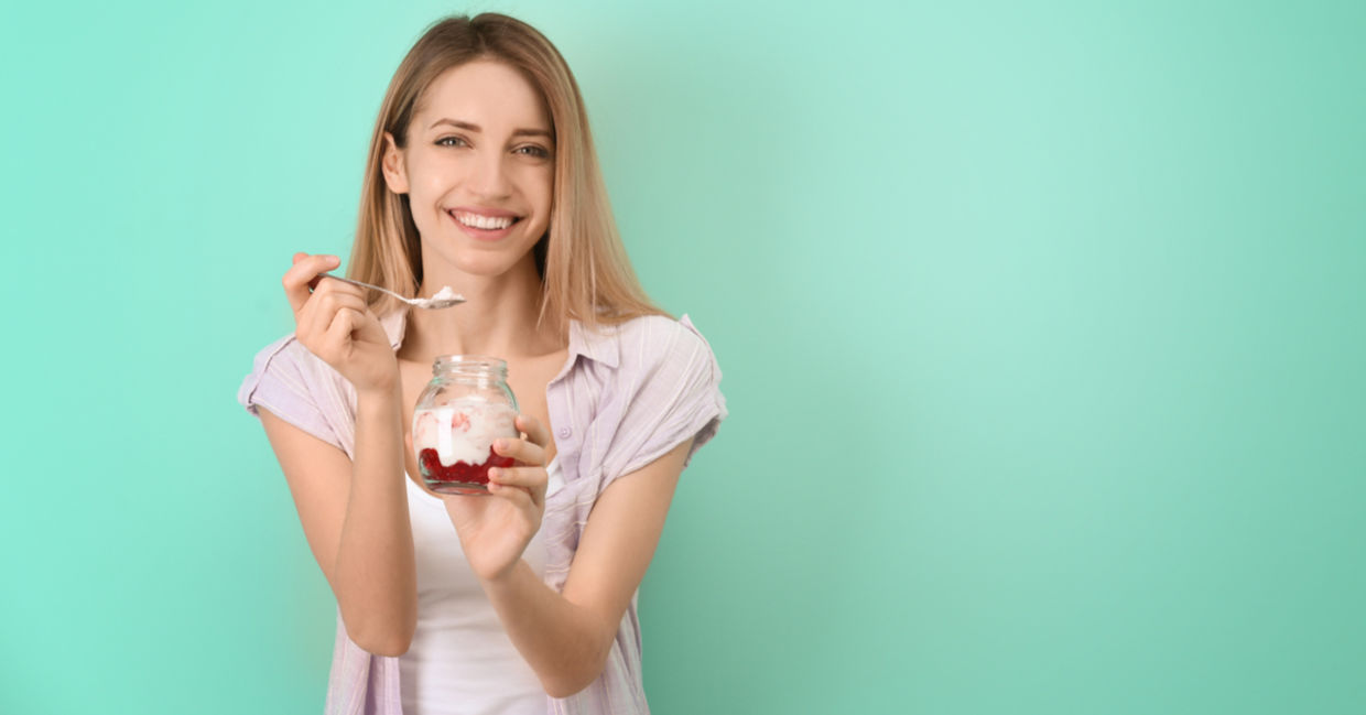 一个年轻女子正在吃酸奶的酸味早餐，果奶和水果。
