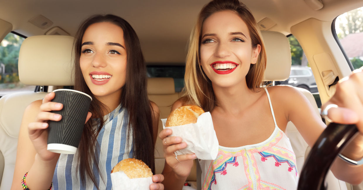 年轻妇女在汽车上吃快餐。