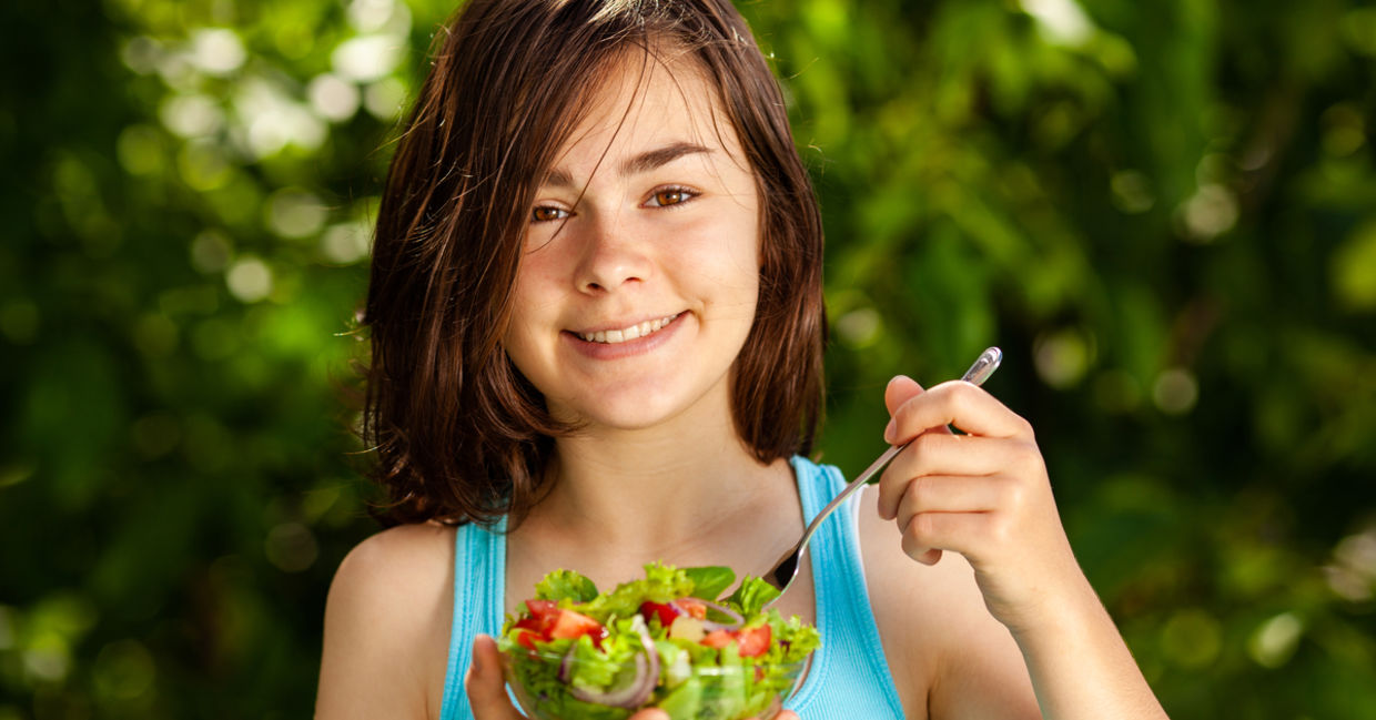 Girl eating fresh vegetable salad.