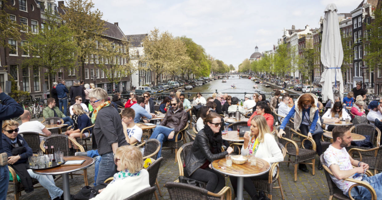 人们享受坐在阿姆斯特丹户外咖啡馆里的Gezellig生活。