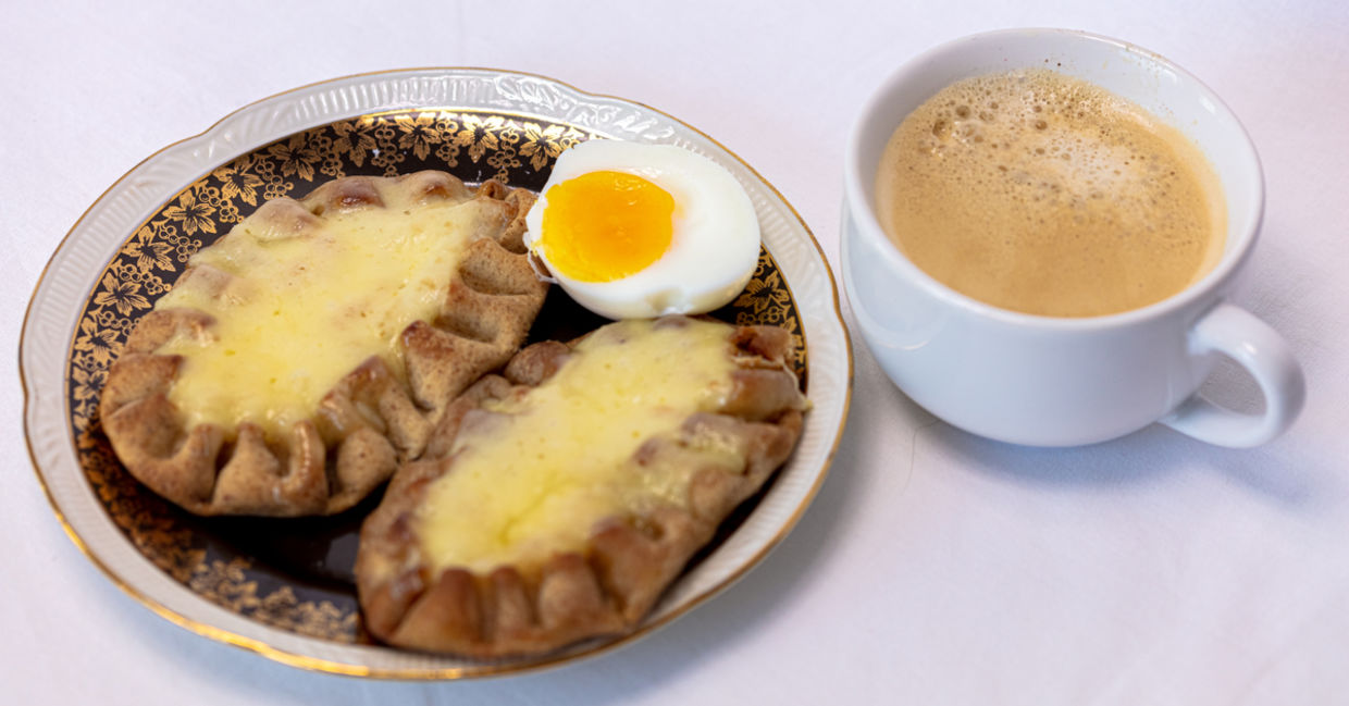 Cup of coffee and Traditional Finnish Karelian pies on a plate.