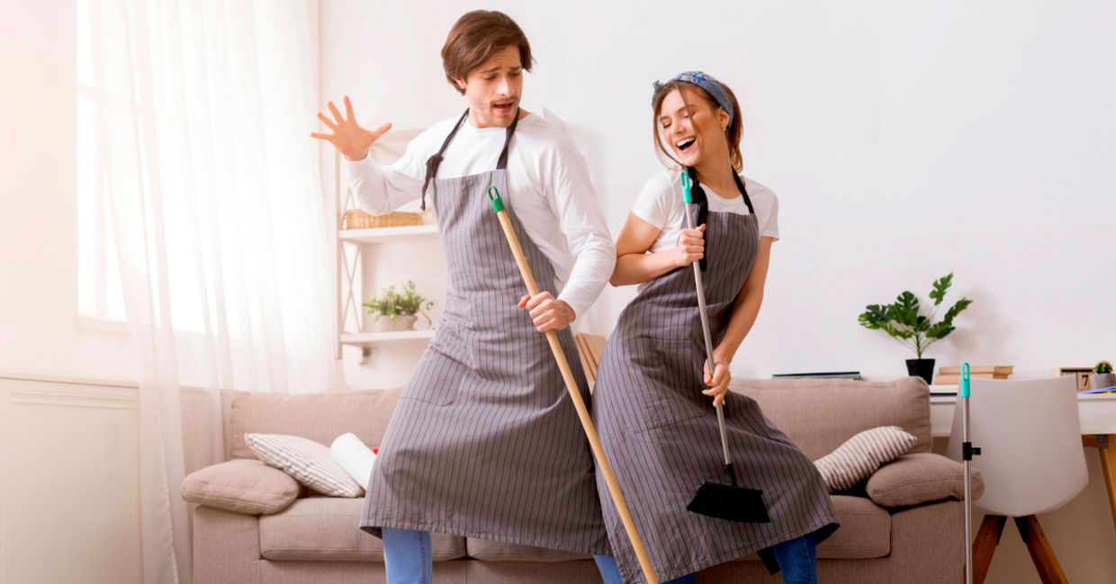 开朗的夫妇获得乐趣和跳舞，当春天打扫他们的家时。