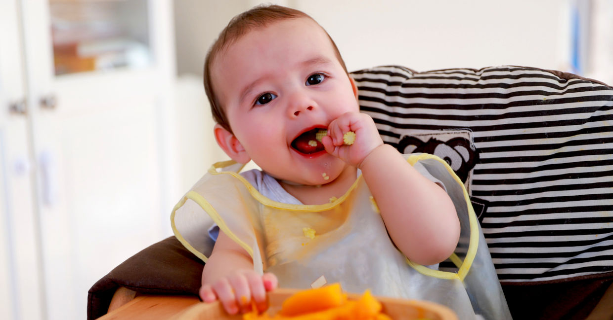 可爱的婴儿吃煮熟的蔬菜。