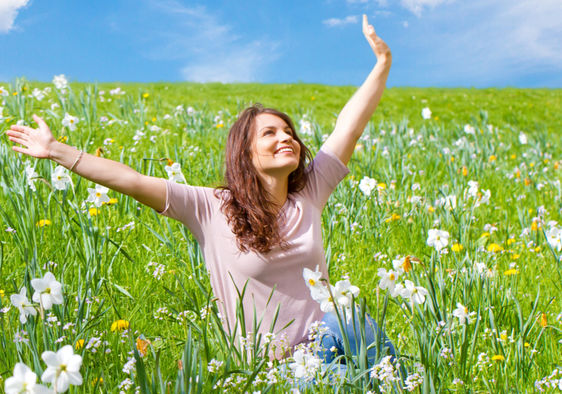 Happy woman sitting in a field of daffodils.